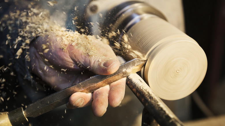 closeup of a woodworker performing woodturning cuts