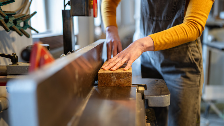 A woodworker flattens a board with a jointer.