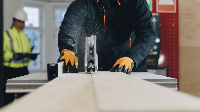 A person off-camera cuts a wooden board with a table saw.