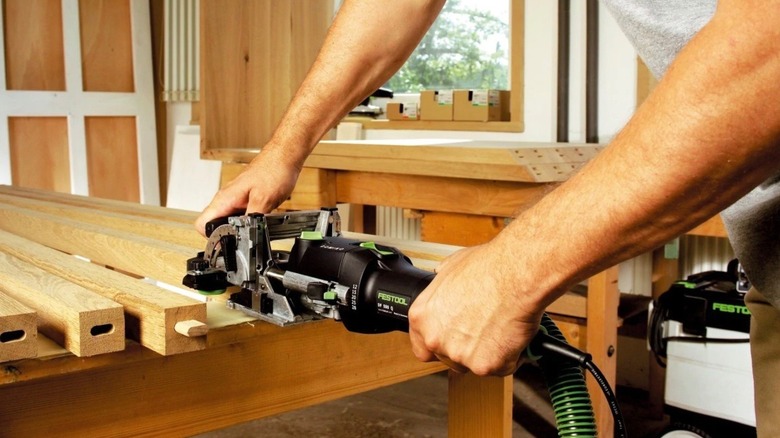 Hands using a Festool domino jointer in a building in construction.