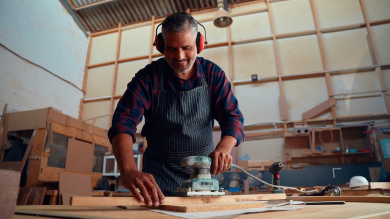 A view from below of a person using a wired sander in a workshop.