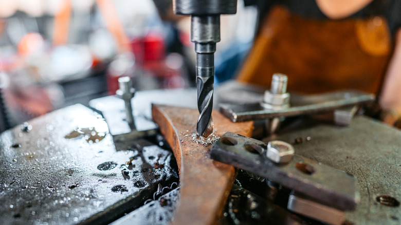 A closeup of a drill press being used to cut metal.