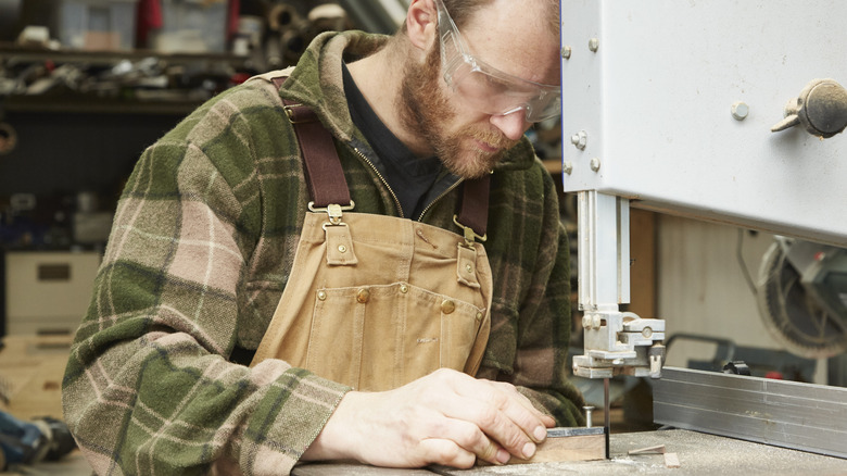 A woodworker using a bandsaw in a workshop