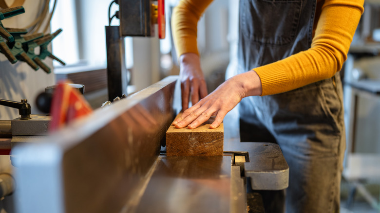 A person uses a large jointer, the background is blurry