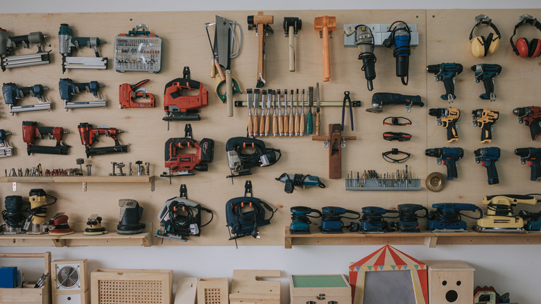 Various hand tools lined up on a workshop wall.