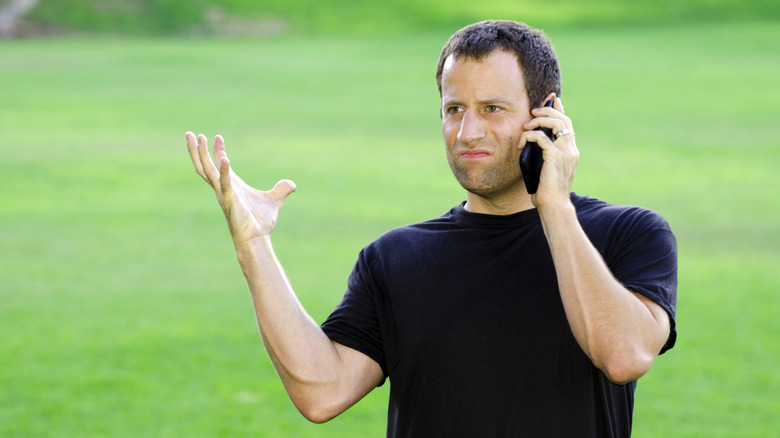 A frustrated man talking on the phone outside