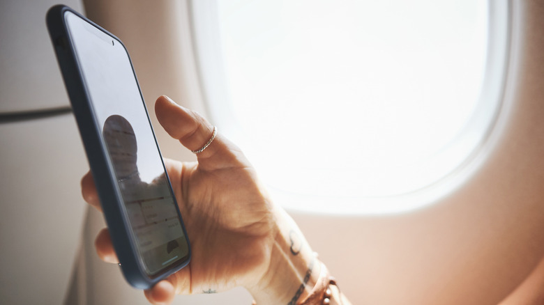 A person using a smartphone on a plane