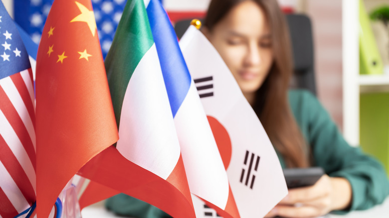 A bunch of flags in front of a woman using her phone