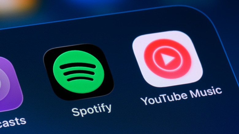YouTube Music and Spotify app icons on a smartphone