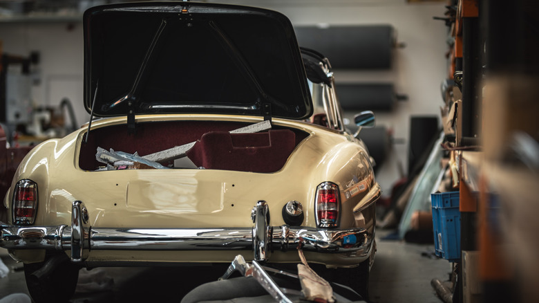 Classic Mercedes in repair shop with trunk open, rear-view