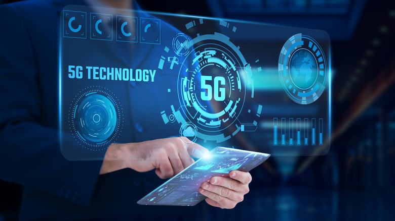 Man holding a fictitious tablet showing graphics of 5G technology