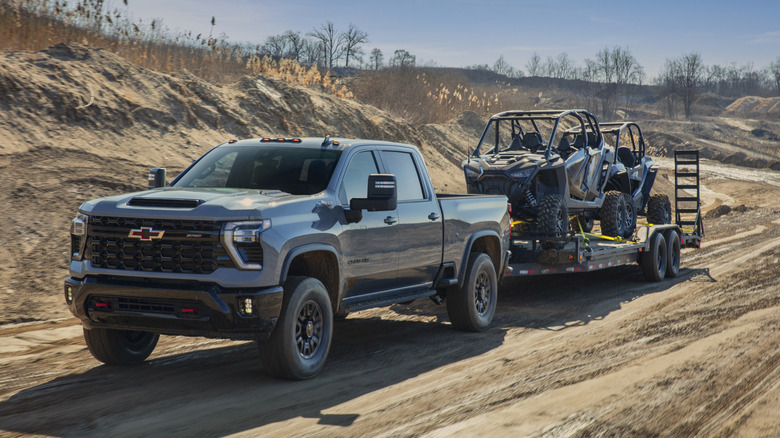 Chevrolet Silverado HD ZR2 towing trailer with ATVs on dirt trail
