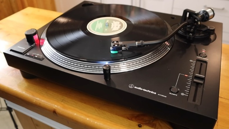 Audio-Technica AT-LP120XBT playing a record on a wooden surface.