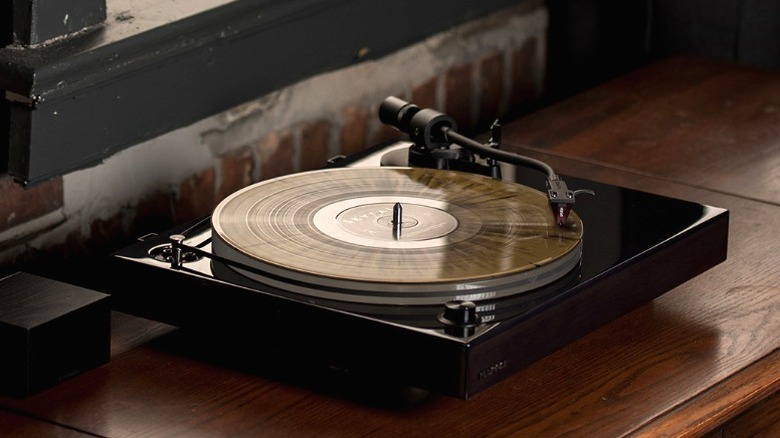 Black Fluance RT85 playing a record in a rustic home with red-brick walls.
