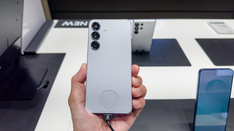Person holding a Samsung S25+ on display in a shop