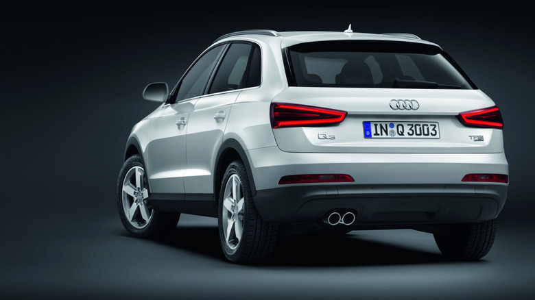A white Audi Q3 from two generations ago with its rear facing the camera, with TFSI badging visible on the tailgate.