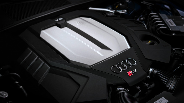 The engine bay of an Audi RS-series car from an unidentified year, showing the V8 and RS badging on the black and silver cover.