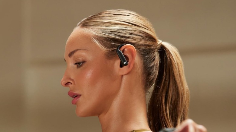 A woman using Beats Powerbeats Pro 2 earbuds