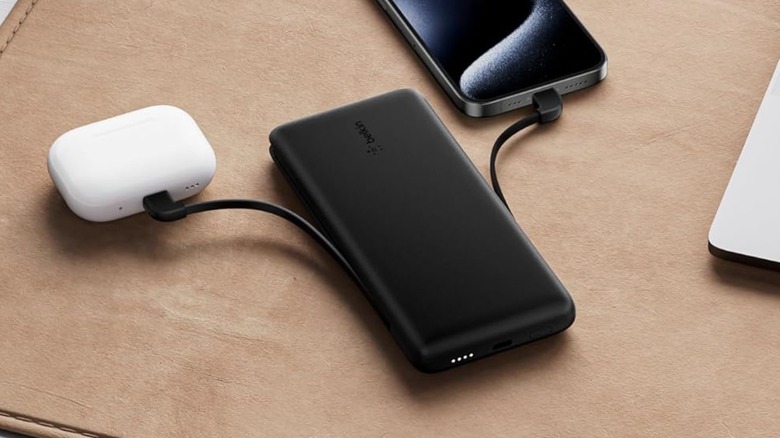 A Belkin portable charger powering earbuds and a phone at the same time