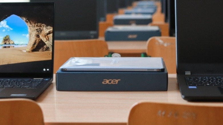 An Acer computer on a desk next to two laptops