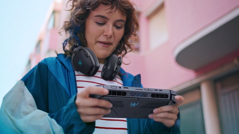 A person using an Acer Predator Atlas 8 handheld outside with headphones around their head