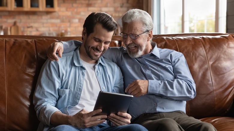 two men smiling at tablet 