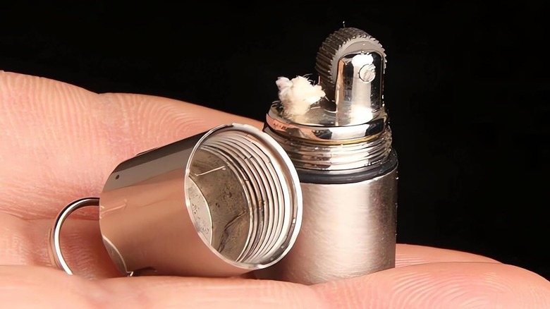 Person holding a tiny kerosene lighter open in their hand.