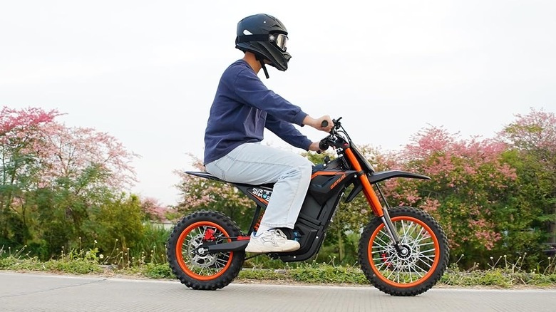 right-side view of young man riding Quiet Ease electric dirt bike on bike path