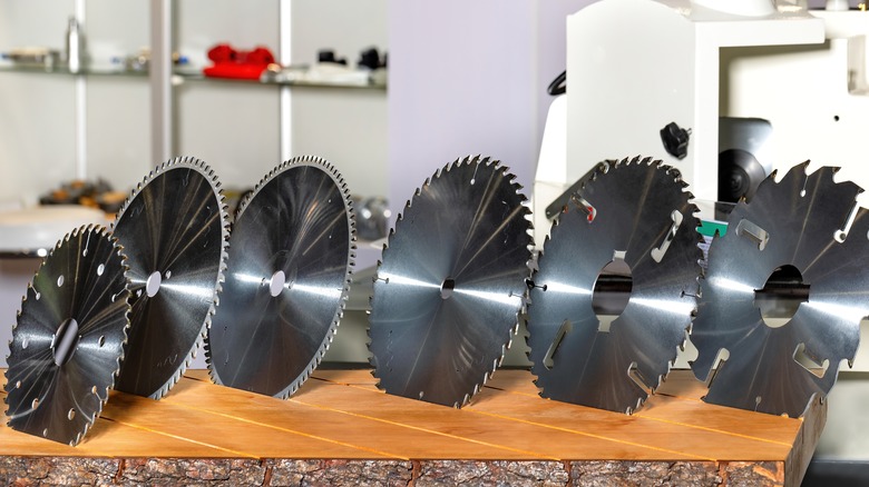 Various circular saw blades sitting up on a wooden table