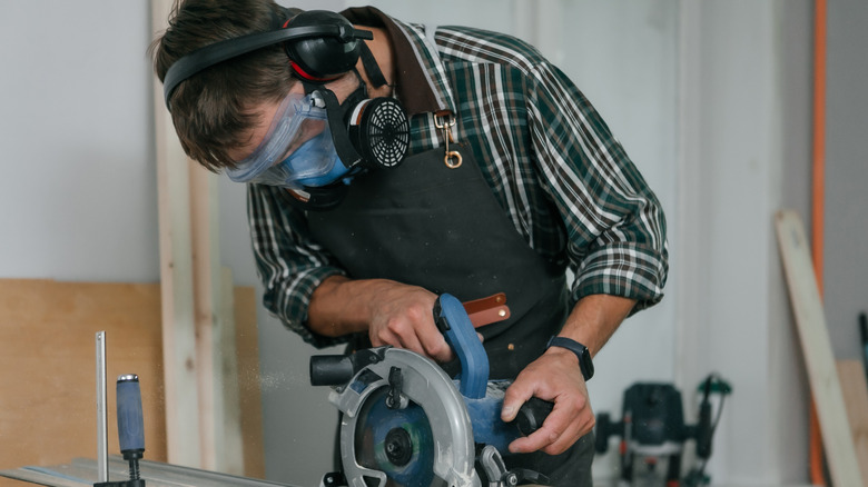 Man wearing safety gear while operating circular saw