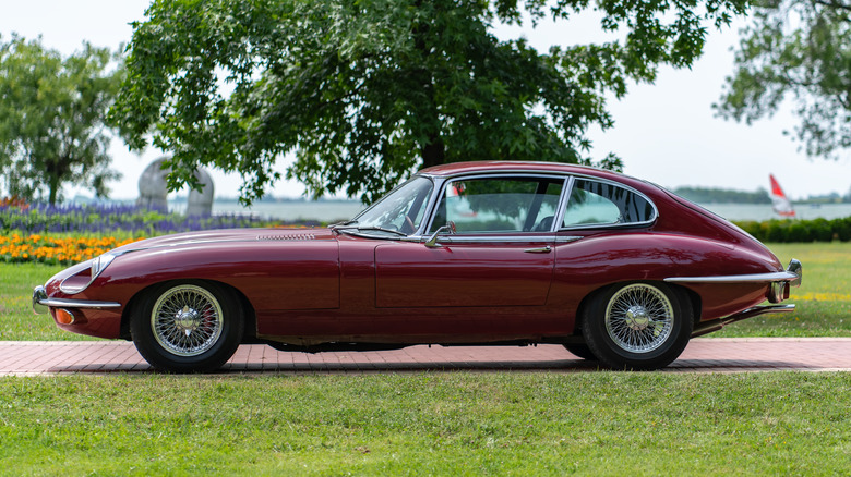 1971 Jaguar E-Type XKE Series III parked on paved path near water.