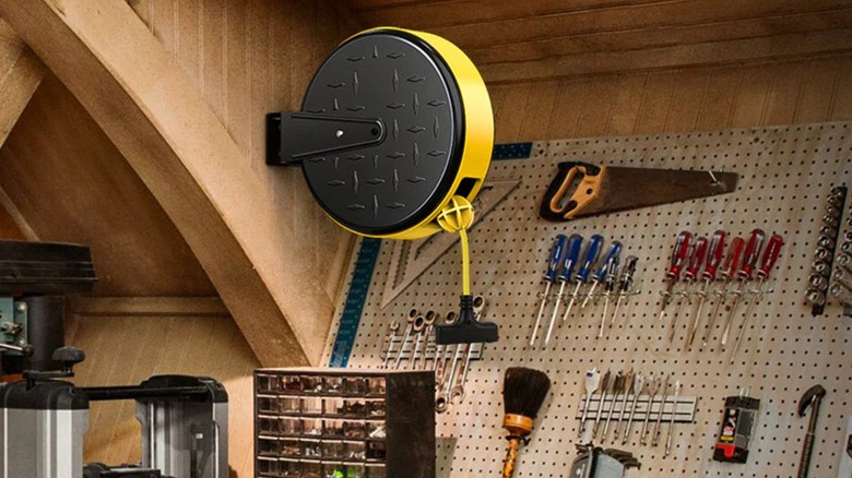 Dewenwils Retractable Extension Cord Reel mounted with other tools in a garage