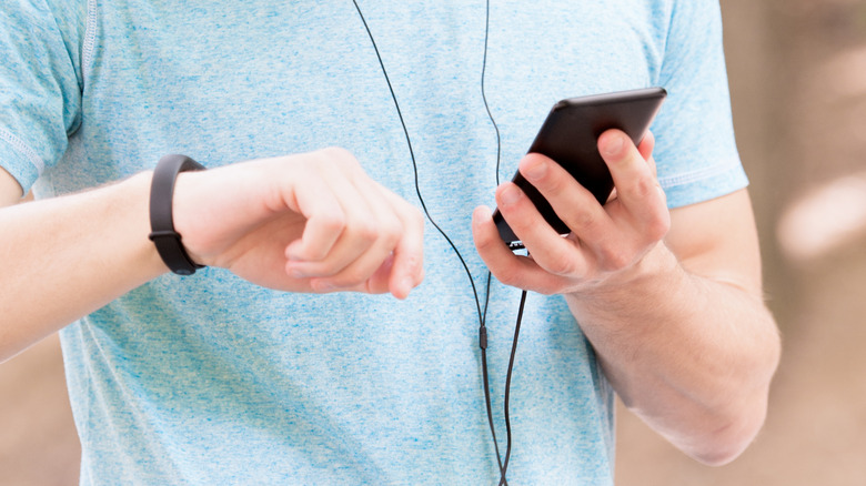 holding a Fitbit and smartphone