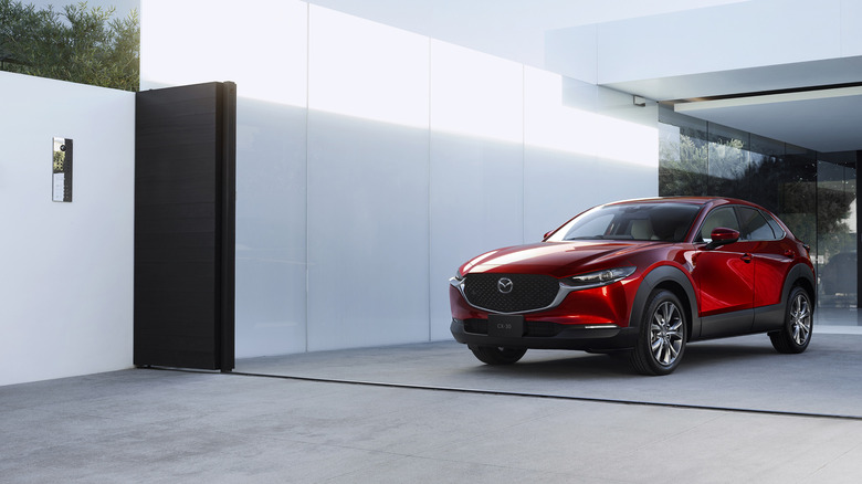 A 2019 Mazda CX-30 SUV parked in front of a modern white building, finished here in red metallic paint.