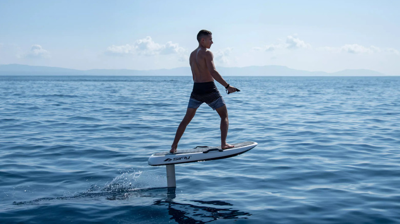 A man in a swimming suit riding an e-foil on a body of water
