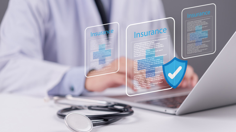 a faceless medical professional is looking up different insurance types on a laptop