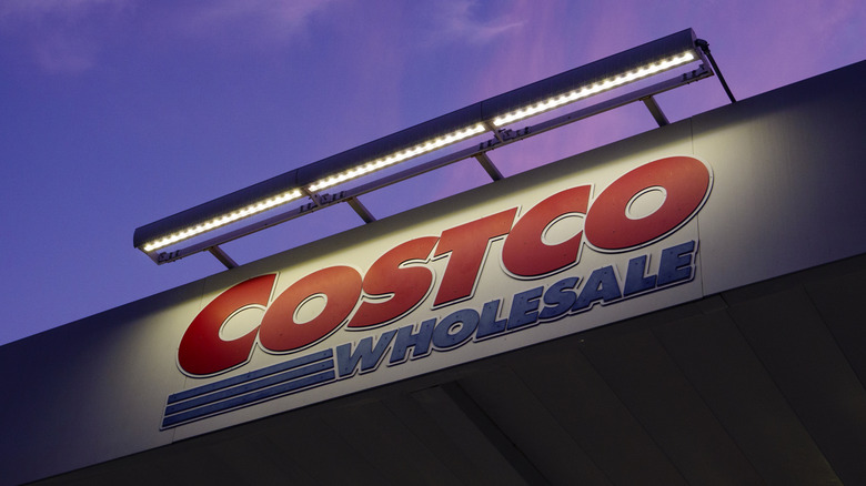 the costco wholesale store logo is shown under bright lights against an evening sky