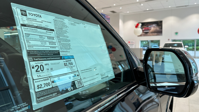 A black Toyota Thundra window sticker taped to the front passenger side window inside a car dealership.