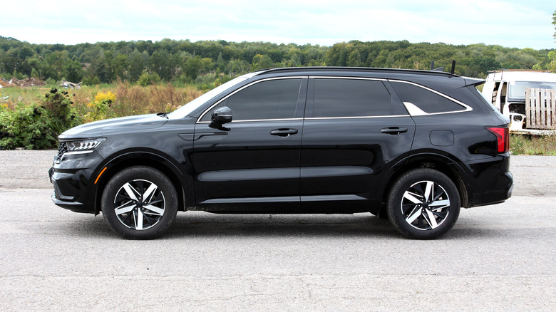 A side-profile shot of a black family SUV with heavily tinted windows.