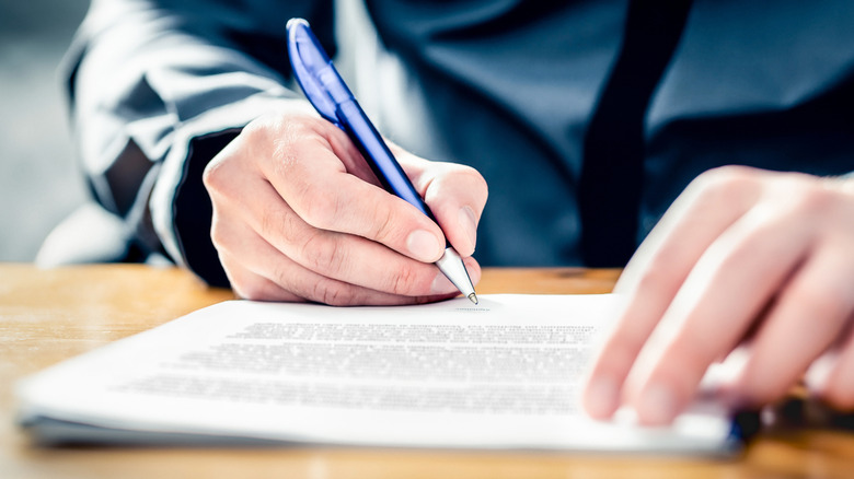 A close-up shot of a person signing a written form.