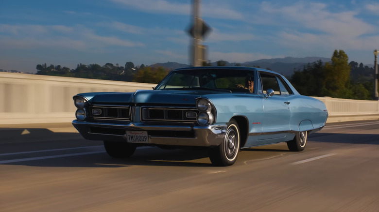 A blue Pontiac Firebird Trans Am being driven down a road.