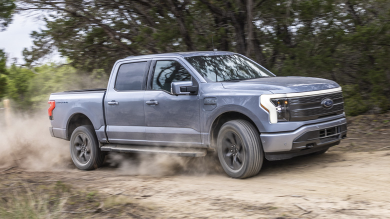 A gray Ford F-150 Lightning driving on a dirt road