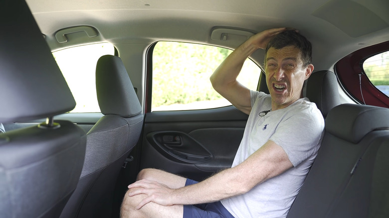 Mat Watson, presenter of carwow, pulling a face while measuring the headroom in a 2021 Toyota Yaris in the UK.