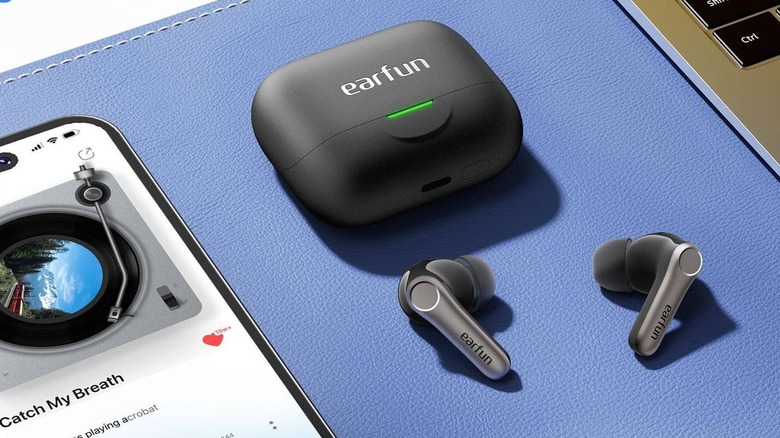 The Earfun Air Pro 4+ on a blue mat next to a smartphone