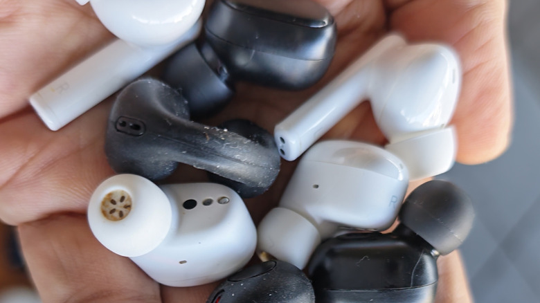 Close up of a hand holding several pairs of earbuds.