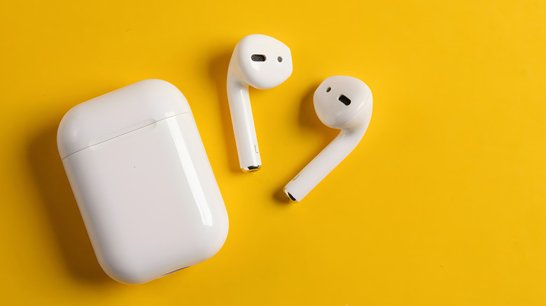 A pair of wireless earbuds on a yellow background