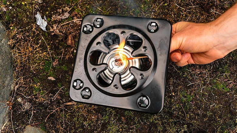 Lighting up a portable camp stove with a match stick.