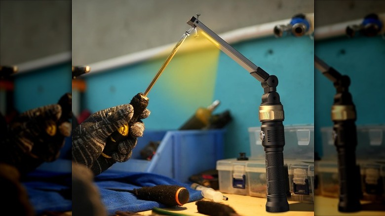 Man pointing a screwdriver toward a foldable work light.