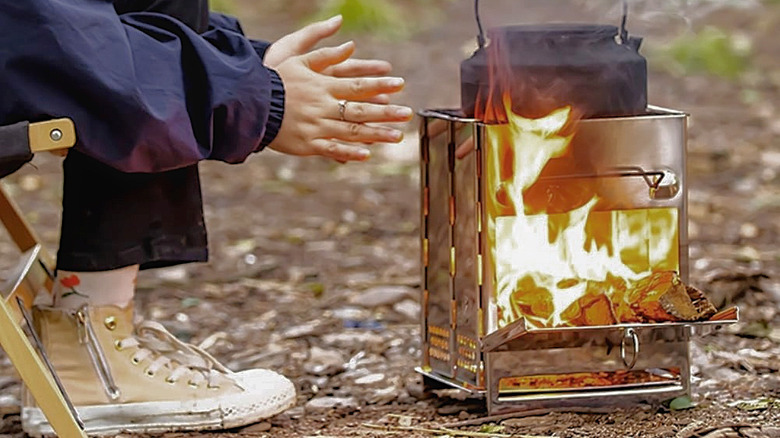 Someone cooking and keeping their hands warm next to the Redcamp Wood Burning Camping Stove/