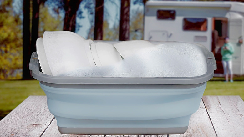 A Tiawudi Collapsible Sink holding dishes at a campground.
